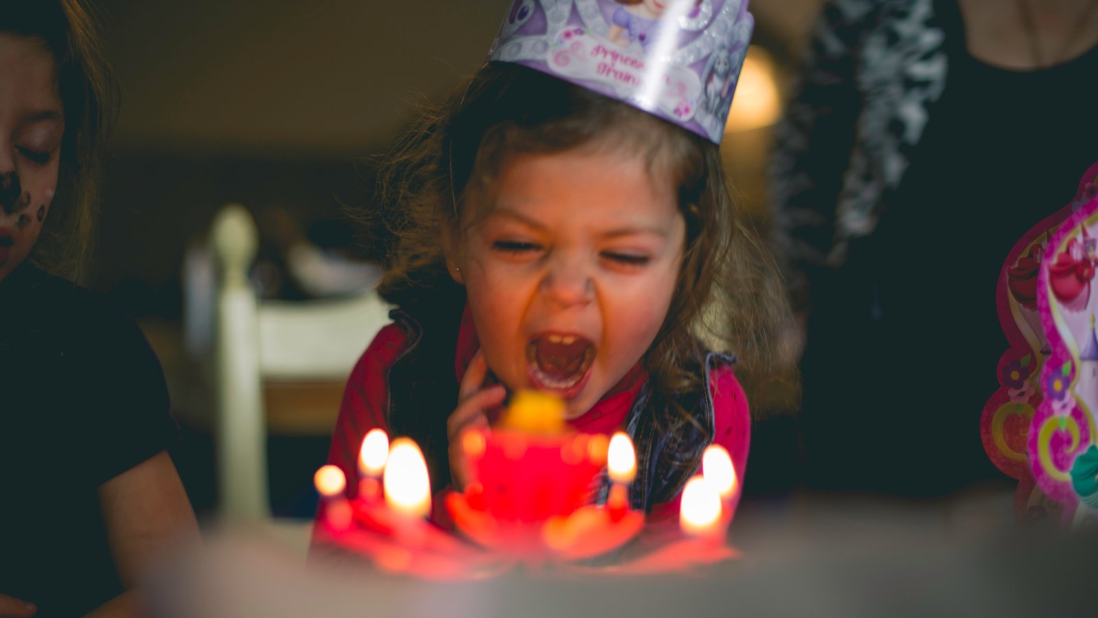 Small girl blowing the candles on her birthday cake